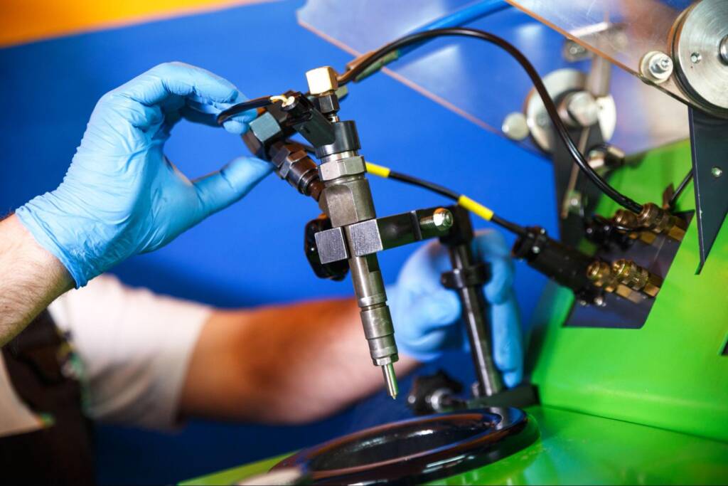A cropped shot of a mechanic testing a diesel fuel injector in his workshop.