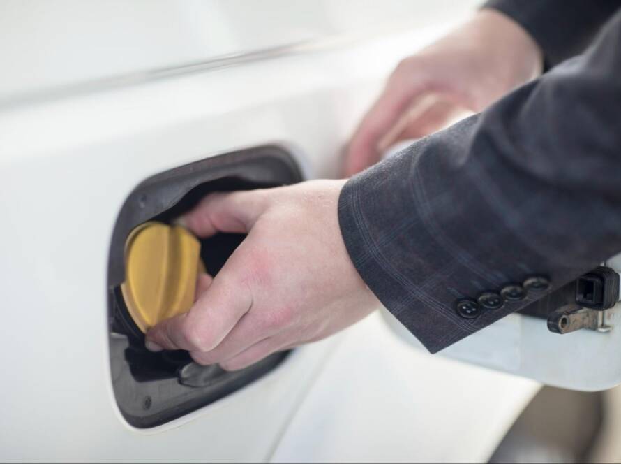 Hand screwing in a fuel cap on a car.