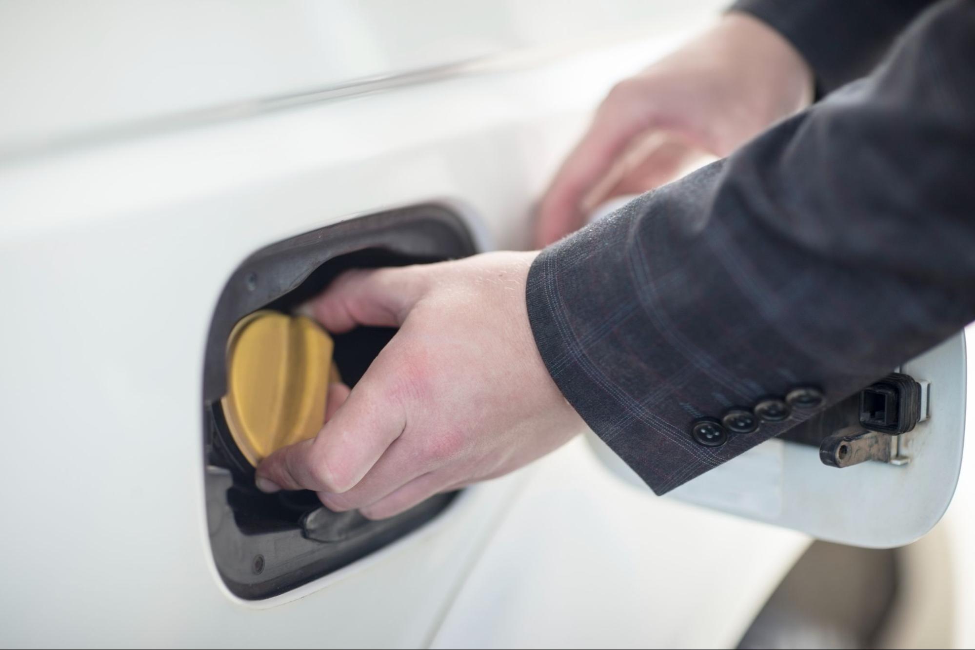 Hand screwing in a fuel cap on a car.