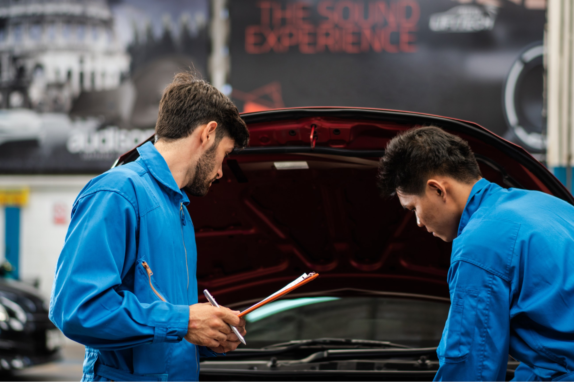 Two mechanics looking under the hood of a car
