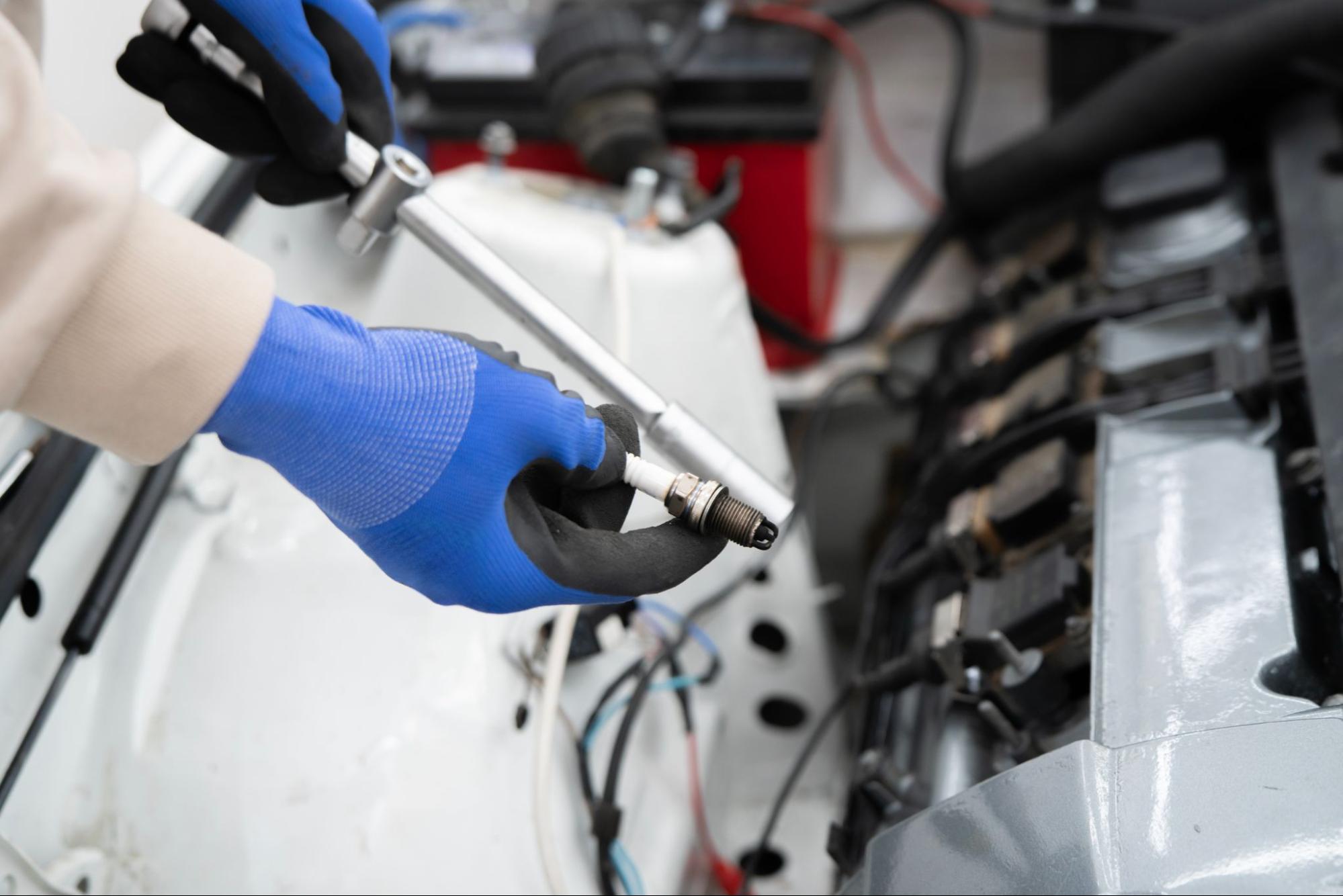 Gloved hand of a mechanic conducting fuel injection testing on a car engine.