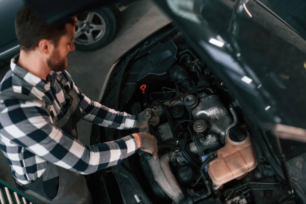Overhead view of a mechanic repairing a car engine.