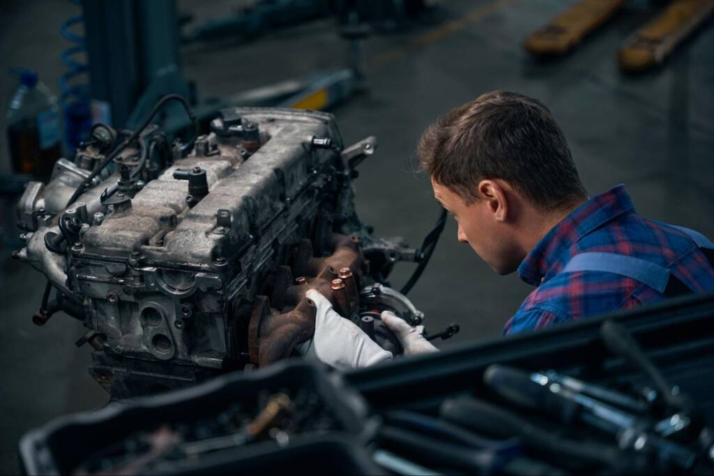 Mechanic installing an exhaust manifold during an engine rebuild process.