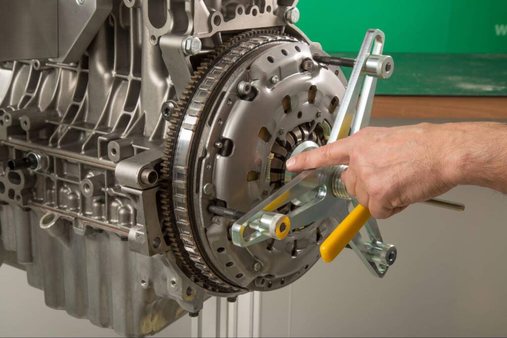 Close-up of a mechanic’s hand working on a car clutch during replacement.