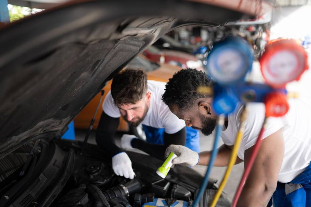 Two auto technicians evaluating vehicle performance during a repair inspection.