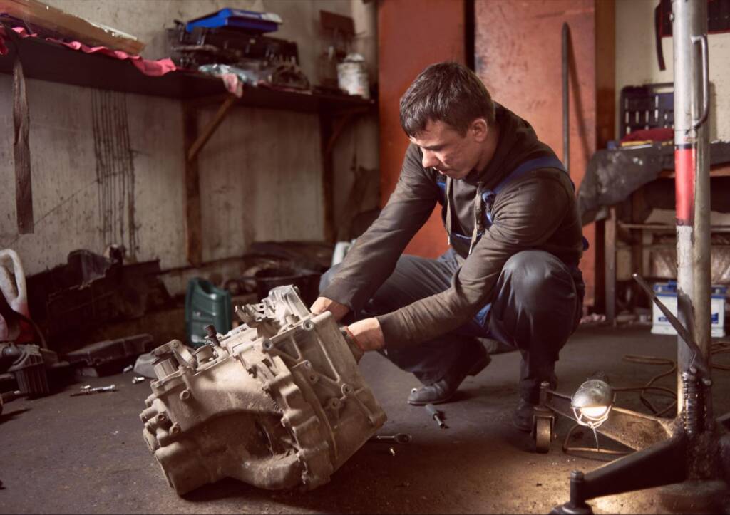 An auto technician repairing a car engine at a service station.