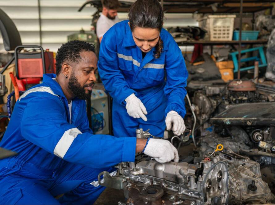 Two diverse auto mechanics working together to rebuild an engine.