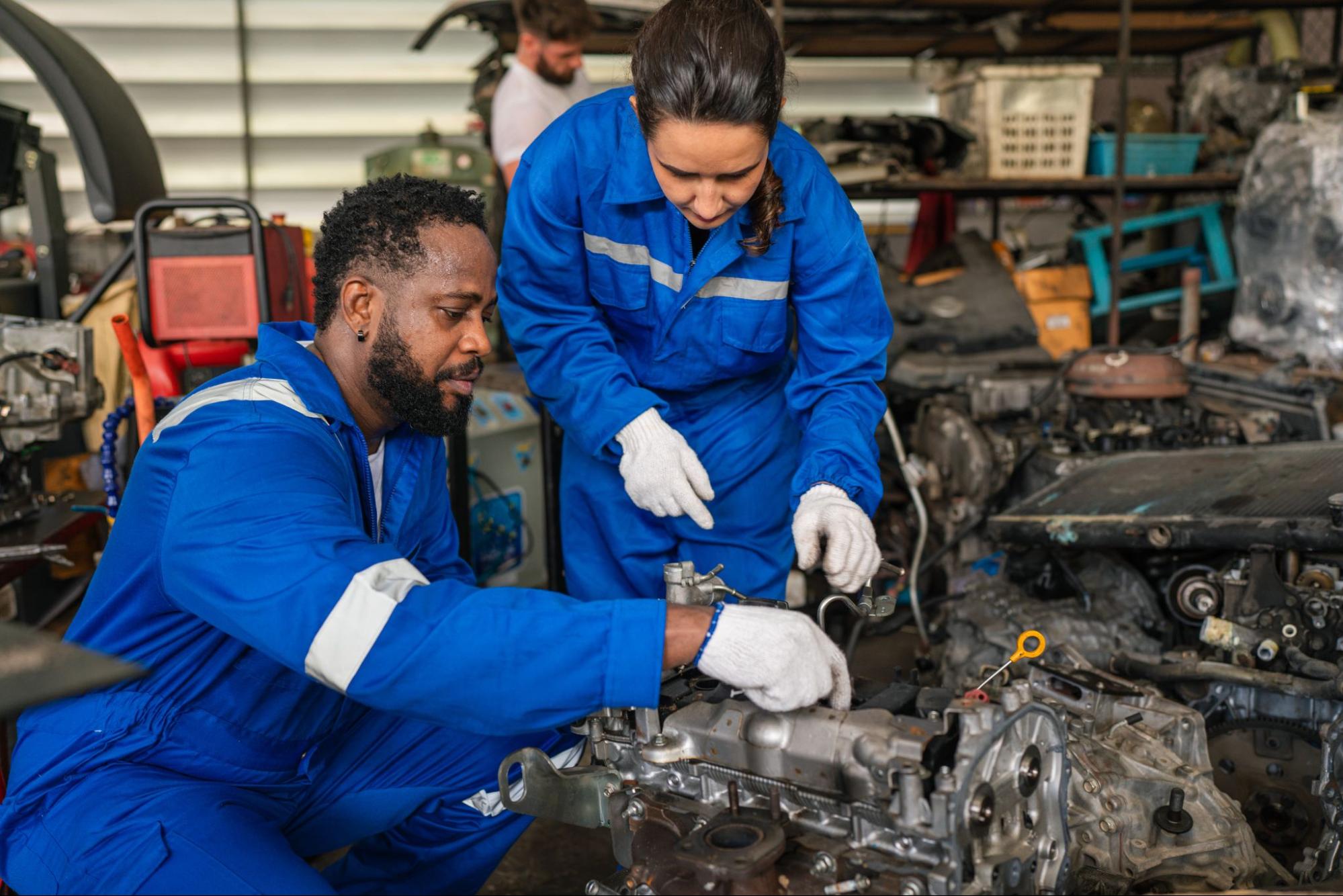 Two diverse auto mechanics working together to rebuild an engine.