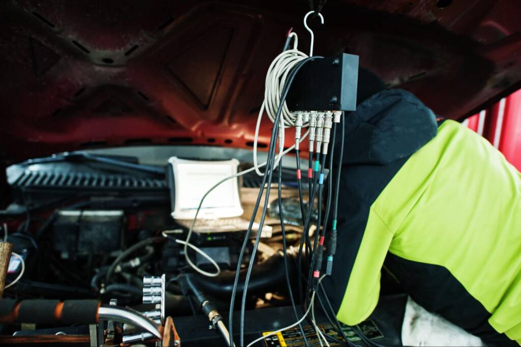Technician begins diagnostic setup on an American SUV in a service garage.