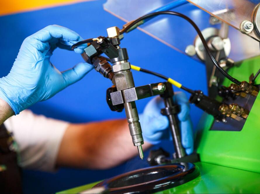 Mechanic testing a diesel fuel injector with diagnostic tools in a workshop