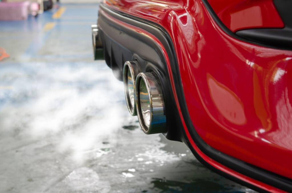 Exhaust fumes trailing from red sports car under acceleration